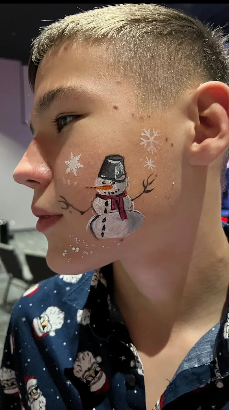 A snowman with a top hat and scarf painted on a child’s cheek