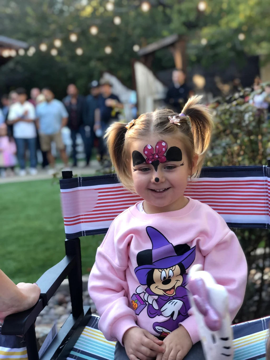 A smiling toddler with a Minnie Mouse face painting design