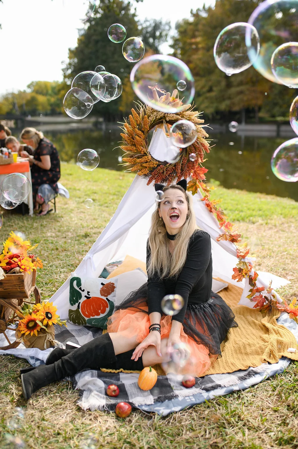 Soap bubbles drifting past a delighted performer beside a decorated teepee